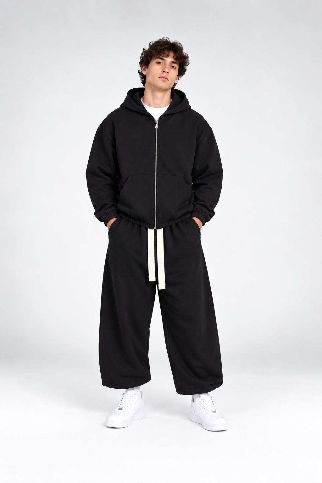 Tuta TRACKSUIT WALF nera in felpa, composta da felpa con cappuccio e pantaloni ampi con cordoncino bianco a contrasto.